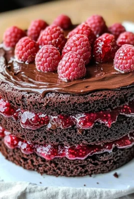 Decadent Chocolate Raspberry Cake topped with fresh raspberries and chocolate ganache.
