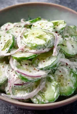 Bowl of creamy cucumber salad with fresh ingredients and herbs