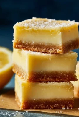 Delicious creamy lemon squares on a plate garnished with lemon zest