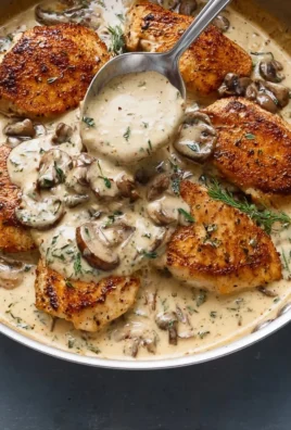 Creamy mushroom chicken dish garnished with herbs on a plate.