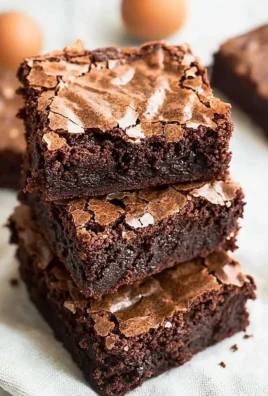 Fudgy brownies with a crackly top displayed on a rustic wooden table.