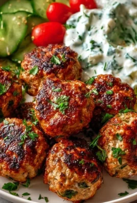 Plate of Greek Turkey Meatballs served with Tzatziki sauce and garnished with herbs.