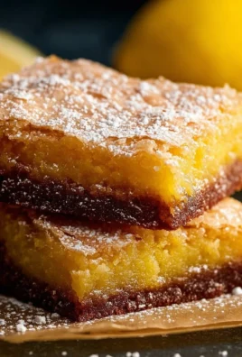 A plate of homemade lemon brownies topped with a dusting of powdered sugar.