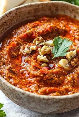 A bowl of muhammara dip made from roasted red peppers and walnuts, garnished with olive oil.