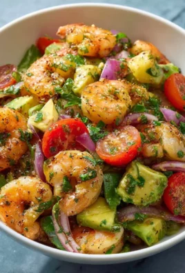 A vibrant shrimp salad with fresh vegetables and dressing served in a bowl
