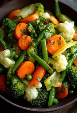 A vibrant steamed vegetable medley featuring carrots, broccoli, and bell peppers.