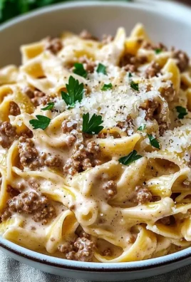 Creamy ground beef pasta served in a bowl with herbs on top.