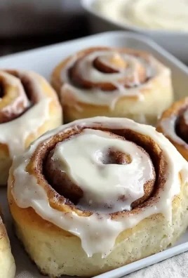 Freshly baked homemade cinnamon rolls with frosting on a cooling rack