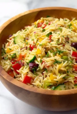 Colorful and fresh orzo pasta salad with vegetables and dressing