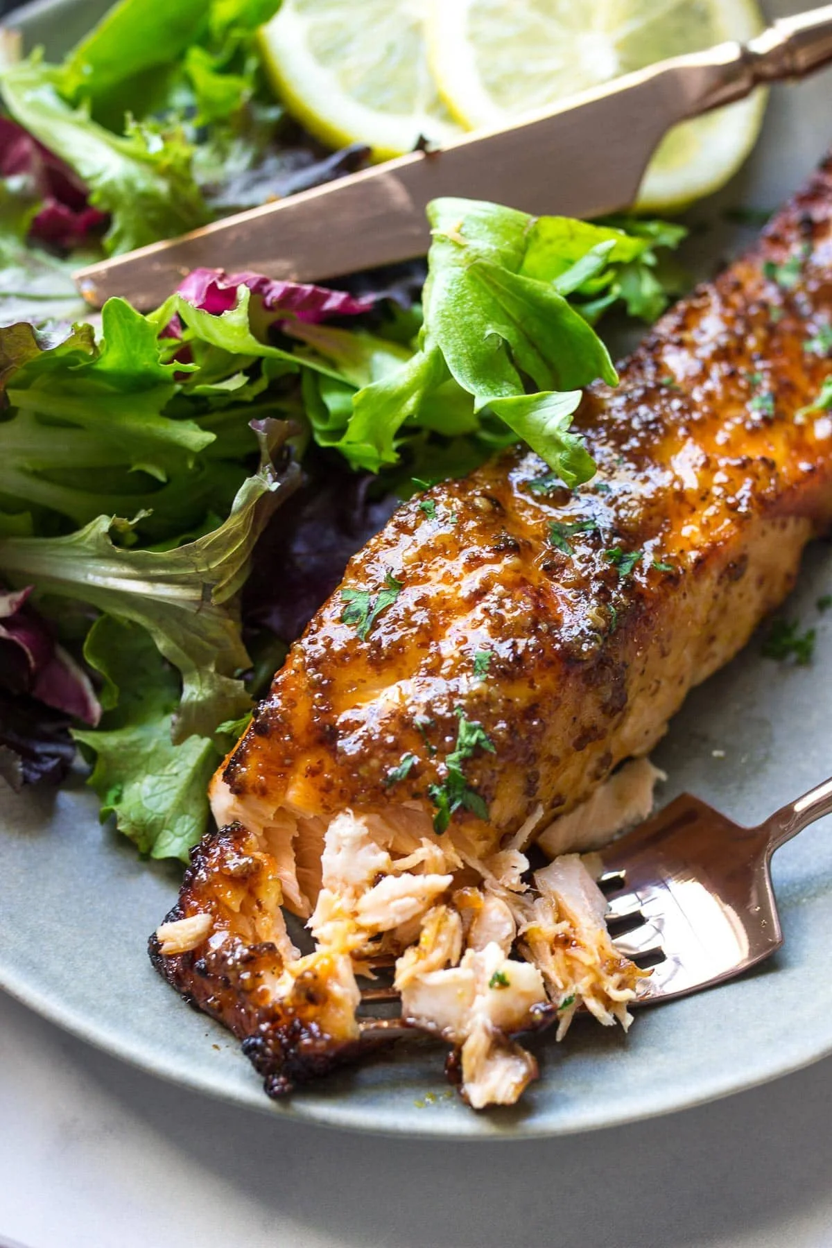 Air Fryer Honey Mustard Salmon served on a plate with fresh herbs and lemon slices