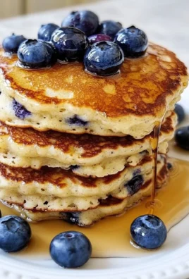 Fluffy blueberry pancakes stacked with fresh blueberries on top