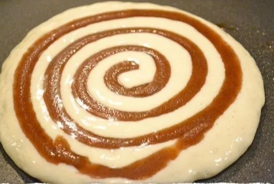 Fluffy cinnamon roll pancakes drizzled with icing on a plate