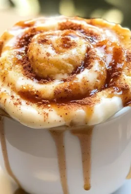 Cottage cheese cinnamon roll mug cake topped with icing in a mug