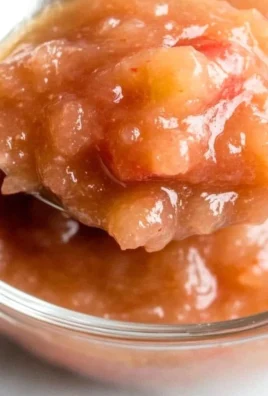 Bowl of homemade strawberry rhubarb applesauce served with fresh strawberries.