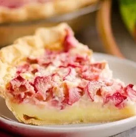 Slice of rhubarb custard pie with a flaky crust and fresh rhubarb topping.