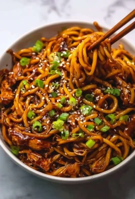 Delicious sticky garlic chicken noodles served in a bowl with fresh garnishes.