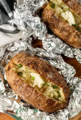 Delicious grilled baked potatoes with herbs on a BBQ grill.