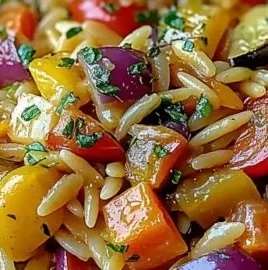 Bowl of roasted vegetable orzo topped with fresh herbs and vibrant veggies