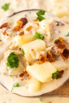 Delicious bowl of New England clam chowder topped with herbs and crackers