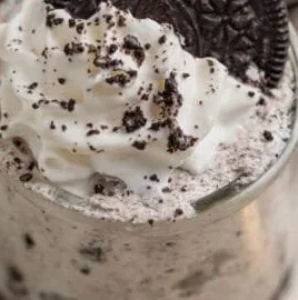 Delicious Oreo no-bake cheesecake cups garnished with whipped cream and Oreo crumbs.