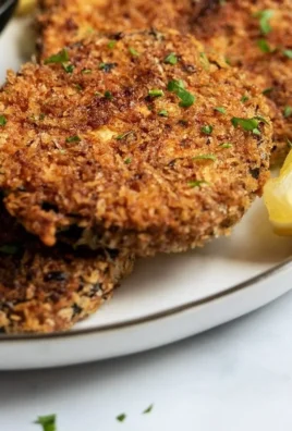 Oven-baked crispy eggplant served on a plate, garnished with herbs.