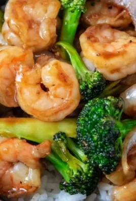 Shrimp stir fry with broccoli served in a bowl, garnished with sesame seeds.