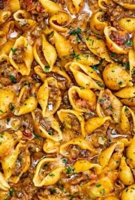 Creamy beef and shells dish served in a bowl with herbs and cheese