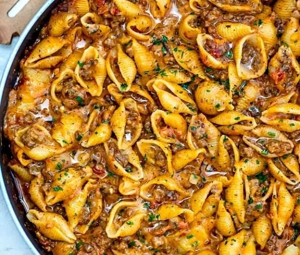 Creamy beef and shells dish served in a bowl with herbs and cheese
