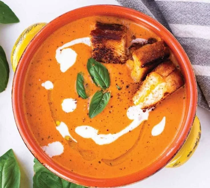 Bowl of creamy tomato basil bisque topped with fresh basil leaves