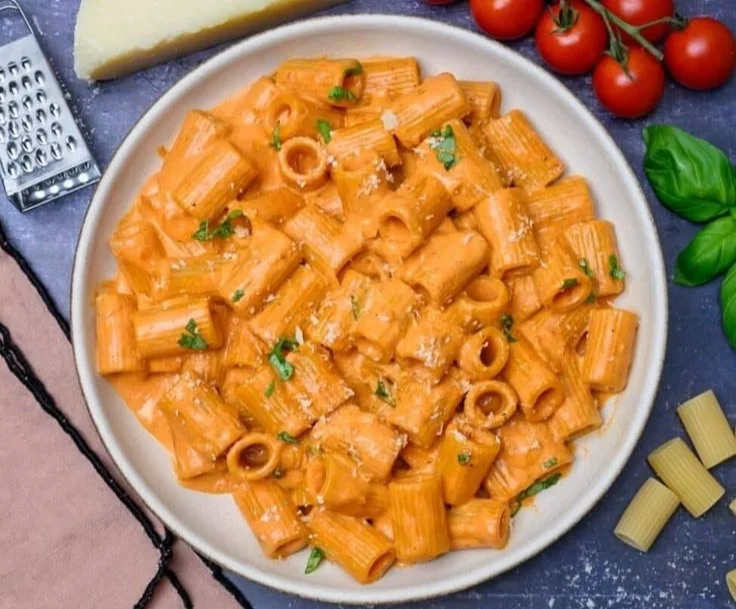 Bowl of creamy tomato pasta sauce with pasta and fresh ingredients