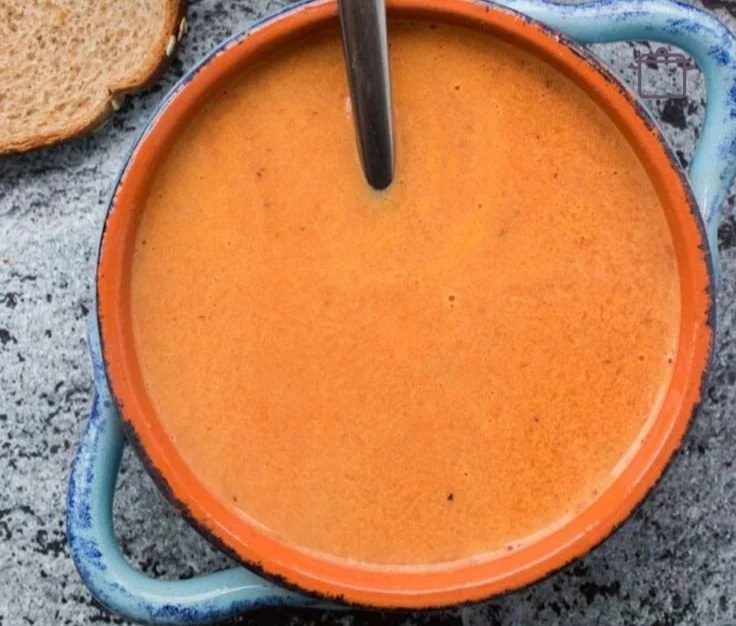 Bowl of creamy tomato soup topped with fresh basil and a swirl of cream.