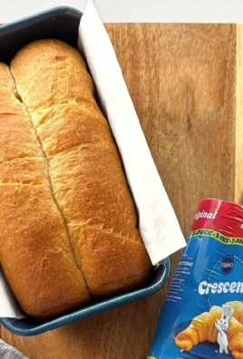 Freshly baked crescent roll loaf sliced on a wooden board.