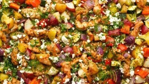 Greek sheet pan chicken with roasted veggies on a serving platter