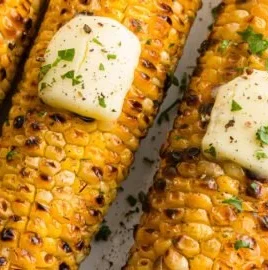 Grilled corn on the grill with seasoning and herbs