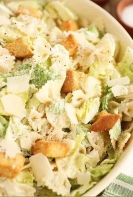 A vibrant Pasta Caesar Salad with greens, croutons, and creamy dressing.