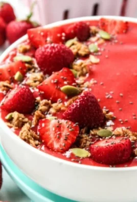 Delicious and colorful strawberry smoothie bowl topped with fresh fruit and granola
