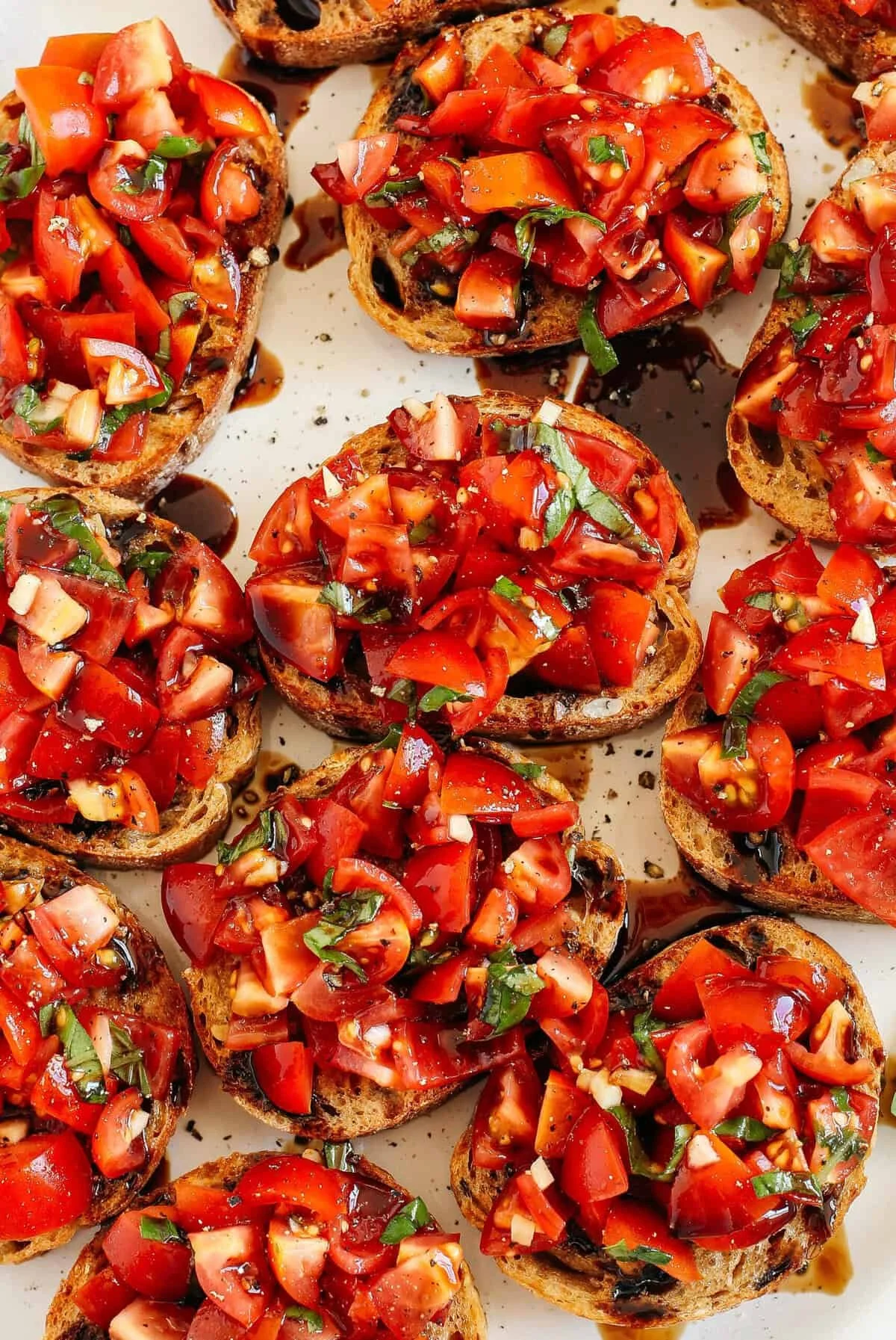 Plate of fresh tomato and basil bruschetta garnished with herbs.