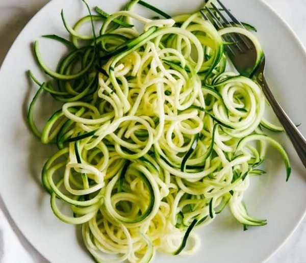 Healthy zucchini noodles served with fresh vegetables and sauce